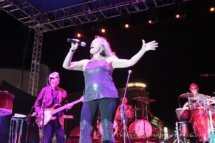 Deb wearing a shine, "disco-ball" top and singing her heart out on stage with the band behind her.