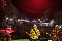 A shot from the stage, showing a huge crowd at a street concert with the bassist, guitarist and backing singer in the foreground.